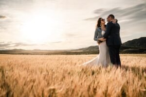 Couple enlacé dans un champ de blé face aux Bardenas - Lumière dorée du matin Couple de mariés enlacé dans un champ de blé doré avec le désert des Bardenas en arrière-plan au lever du soleil