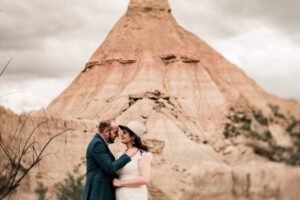 Baiser romantique devant le Castil de Tierra des Bardenas Couple de mariés s'embrassant passionnément devant la formation rocheuse emblématique du Castil de Tierra dans le désert des Bardenas
