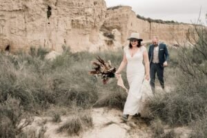 Couple souriant explorant les canyons des Bardenas Reales après leur mariage Mariés souriants en marchant main dans la main dans un canyon spectaculaire du désert des Bardenas